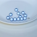 Dettaglio macro di perle in acrilico azzurro perlato con fori per la creazione di gioielli - Blu e Viola