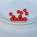 Vista macro di perle acriliche rosse perlate con spilli argentati per gioielli fai da te - Rosso