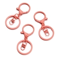 Close-up of three coral pink painted metal lobster clasps and keyrings for DIY crafts - 30x68mm / Deep Pink