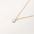 Détail macro du collier doré avec pendentif lettre E en émail blanc sur chaîne fine - Lettre E