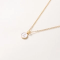 Détail d'un collier doré avec pendentif rond en émail blanc et la lettre L majuscule - Lettre L