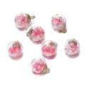 Close-up of glass orb pendants with pink petals and gold caps for DIY jewelry - Pink