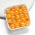 Macro view of 16mm orange iridescent cracked acrylic beads in a white square bowl - Orange