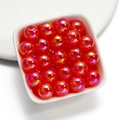 Macro view of 16mm iridescent acrylic beads with orange-red Aurora Borealis finish for DIY - Red
