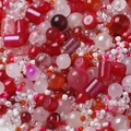 Close-up of red and pink mixed round beads in various textures for DIY jewelry making - Red Series