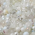 Macro view of assorted white and translucent beads with various textures for DIY crafting - White