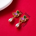 Close-up of golden butterfly earrings with purple gems and white teardrop pearls - Half Butterfly With Pearl