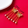 Macro shot of gold butterfly pendant with colorful enamel, tassels, and white pearls - Pink Blue Purple Butterfly Tassel