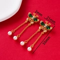 Detail view of butterfly drop earrings with green stones and pearls on red background - Butterfly Double Tassel Green Pearl