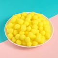 Soft yellow polyester pompoms for DIY crafts and clothing decor stacked on a ceramic plate - 50 Pieces/Pack (1cm Diameter) / Bright yellow
