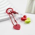 Detail of colorful resin heart charms and red spring clasp on white wavy display - White Red Green Heart