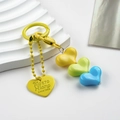 Macro view of colorful resin heart beads and engraved yellow pendant on a keychain - Yellow Green Blue Heart