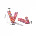 Close-up of pink glitter resin letter V charm with dimensions 41x37.5mm for keychains - Letter V