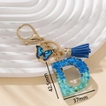 Portachiavi lettera D in resina blu glitterata con ciondolo a farfalla e nappa blu - Blu D