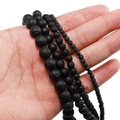 Natural black lava stone beads in various sizes held by hand for jewelry making - 12mm / Black Lava Rock