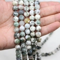 Polished natural tree agate round beads strings with green moss patterns held in hand - 4mm / Tree Agate