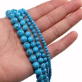 Detailed view of turquoise beads in multiple sizes with dark spiderweb patterns for DIY jewelry - Blue