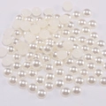 Vista macro de medias perlas blancas de ABS con brillo para creación de joyería DIY - Blanco Roto