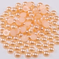Vista detallada de medias perlas de ABS rosa melocotón para manualidades DIY y arte de uñas - Naranja