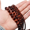 Macro detail of red tiger eye stone beads in various sizes with silk luster finish - Small Diameter (6mm) / Reddish Brown