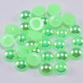 Macro shot of light green AB flatback half pearls with iridescent finish for DIY crafts - Green