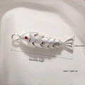 Macro detail of silver articulated fish pendant with red stone eyes and scale textures - Silver 6-Section Fish