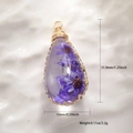 Macro view of handmade drop pendant with purple dried flowers and gold wire wrap - Transparent Resin Purple Dried Flower Style
