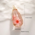 Detailed close-up of water drop resin pendant with pink dried flowers and gold wire wrap - Transparent Resin Pink Dried Flower Style