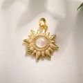 Golden sun pendant with mother of pearl center and white pearl accents on white fabric - Sun