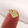 Ciondolo rettangolare dorato con incisione Good Luck tenuto tra le dita - Stile Rettangolo Piccolo Good Luck (A0371)