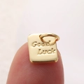Ciondolo quadrato dorato con incisione Good Luck mostrato sulla punta del dito - Stile Quadrato Oro Good Luck (A0375)