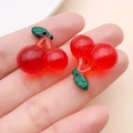 Macro shot of translucent red resin cherry pendant with green leaves and top hole detail - Clear Red 3D Glitter Cherry (24386)