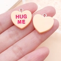 Gros plan de pendentifs en résine en forme de cœur avec texte Hug Me et anneaux - Jaune Orange HUG ME (24524)
