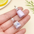 Detail of a mini lavender resin milk bottle pendant held by hand for scale showing a label - Transparent Purple (24077)