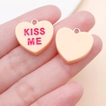 Close-up of heart-shaped resin charms with KISS ME lettering and silver metal loops - Orange Kissme Style