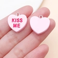 Detail von rosa Herz-Anhängern aus Harz mit Kiss Me Text und silbernen Metallringen - Rosa Kissme-Stil