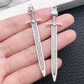 Detailed close-up of silver alloy sword pendants featuring wolf head and textured hilts - Antique Silver Owl Sword (8113)