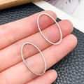 Close-up of silver-plated oval geometric hollow frames for DIY jewelry making accessories - Oval Style (T1878)
