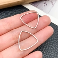 Polished silver shield-shaped hollow metal frame pendant shown on fingertips for scale - Rounded Triangle Style (T1866)