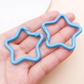 Hand holding two blue star-shaped aluminum alloy keychains for DIY jewelry making - Blue (FT188)