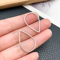 Silver teardrop hollow frame pendants for DIY jewelry making shown on fingertips - Waterdrop Style (T1854)