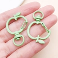 Close-up of mint green apple shaped zinc alloy swivel lobster clasp held in hand - Green