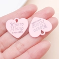 Vue détaillée d'un pendentif cœur rose mat en émail tenu à la main pour l'échelle - 21x23mm / Rose Clair