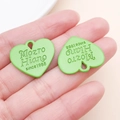 Close-up of light green heart-shaped alloy charms with engraved letters held in hand - 21x23mm / Green