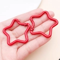 Pair of red star-shaped aluminum carabiners held by hand to show compact size - Red (FT188)