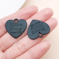 Macro detail of black heart-shaped metal charms with 'Mozto Hiano since 1988' engraving - 21x23mm / Black