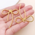 Dettaglio macro di ciondoli a fiocco dorati testurizzati per creazioni di gioielli fai-da-te - 42x37mm / Oro