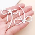 Pendenti a fiocco bianco opaco su mano mostrano scala e trama del gioiello fai-da-te - 42x37mm / Bianco