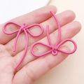 Dettaglio macro del ciondolo a fiocco rosa con finitura a spirale e foro di sospensione - 42x37mm / Rosso rosa