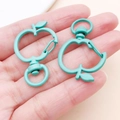 Lake blue and morandi green apple shaped lobster clasps held in hand for DIY jewelry - Dark Green